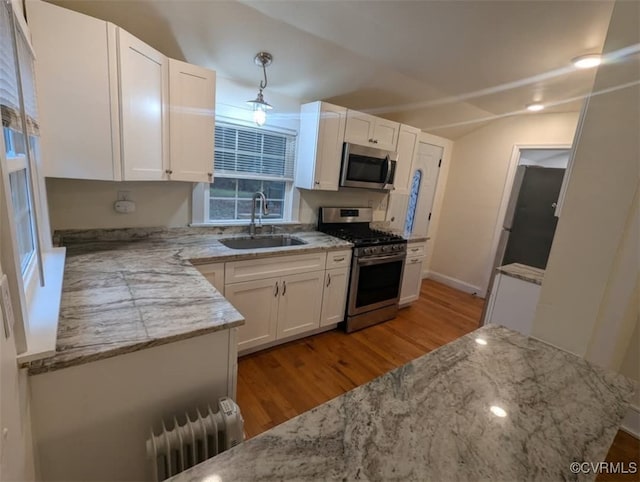 6080 Buckley Hall Rd, Mathews, VA 23035 - kitchen featuring white cabinetry, radiator heating unit, light stone countertops, stainless steel appliances, and a sink