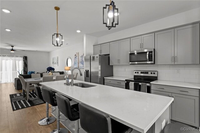 7217 Leire Ln, Chesterfield, VA 23832 - kitchen featuring stainless steel appliances, gray cabinets, a sink, wood finished floors, and decorative backsplash