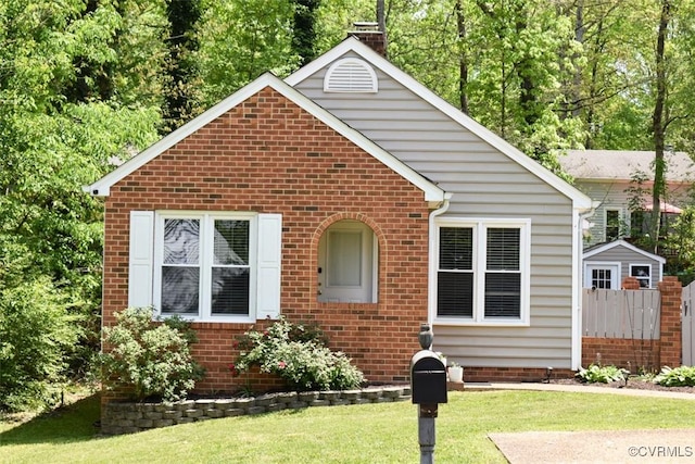 bungalow-style home featuring a front yard, fence, a chimney, and brick siding