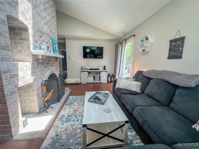 living area featuring a brick fireplace, wood finished floors, and lofted ceiling