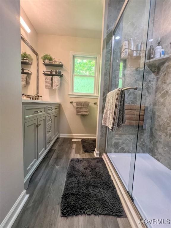 full bathroom with a stall shower, wood finished floors, vanity, and baseboards