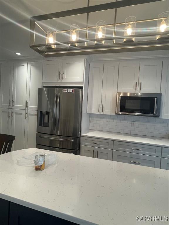 8304 Elizabeth Ann Dr, Hanover, VA 23111 - kitchen with appliances with stainless steel finishes, decorative backsplash, light stone countertops, and a chandelier