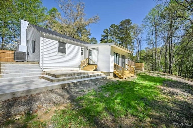back of property with entry steps and a chimney