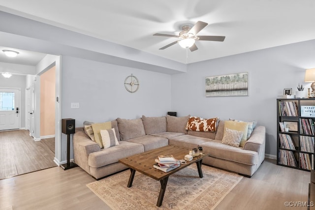 living area with light wood-style floors, baseboards, and a ceiling fan