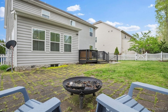 back of property with a wooden deck, fence, a yard, a patio, and a fire pit