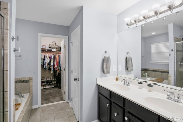 bathroom with double vanity, a sink, a stall shower, and a spacious closet