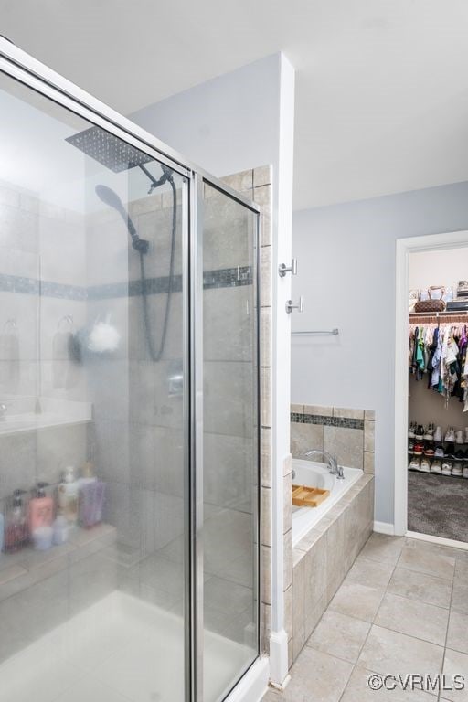 bathroom featuring a walk in closet, tile patterned flooring, a stall shower, and a garden tub