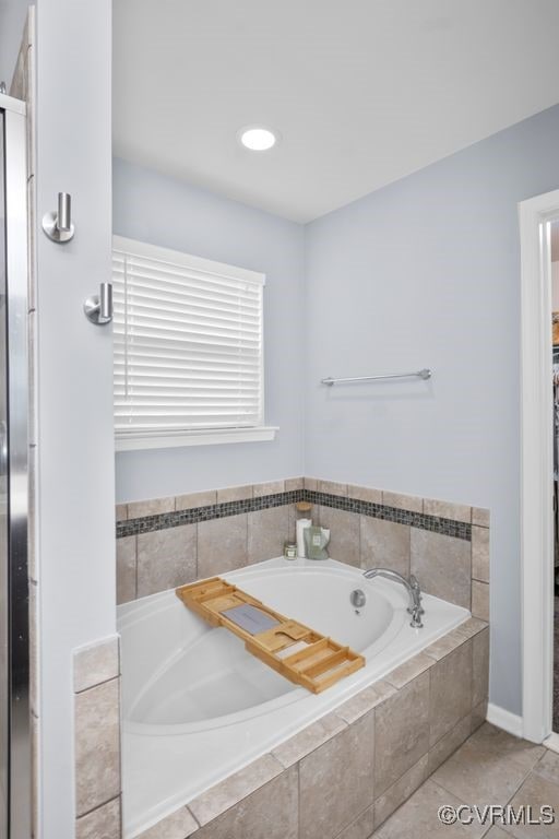 bathroom with tile patterned floors and a bath