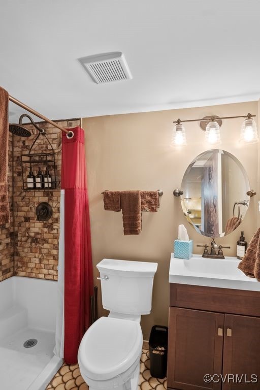 bathroom with vanity, a shower stall, toilet, and visible vents
