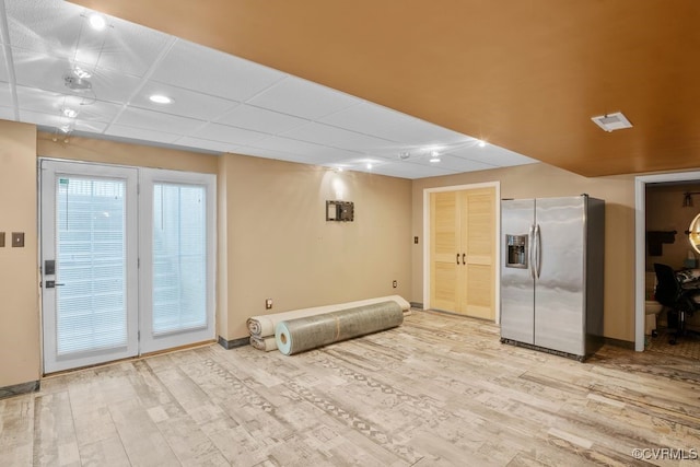 interior space with baseboards, light wood finished floors, and stainless steel refrigerator with ice dispenser