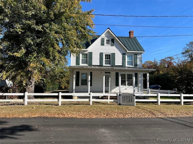 211 Taylor Ave, Urbanna, VA 23175 - farmhouse-style home with a porch, a standing seam roof, a fenced front yard, and metal roof