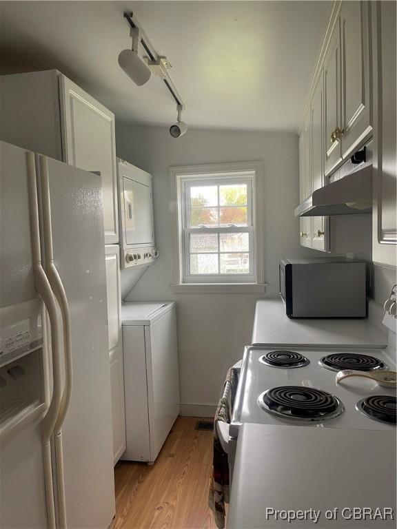 211 Taylor Ave, Urbanna, VA 23175 - kitchen featuring light wood-style floors, under cabinet range hood, stacked washer and dryer, white refrigerator with ice dispenser, and electric range