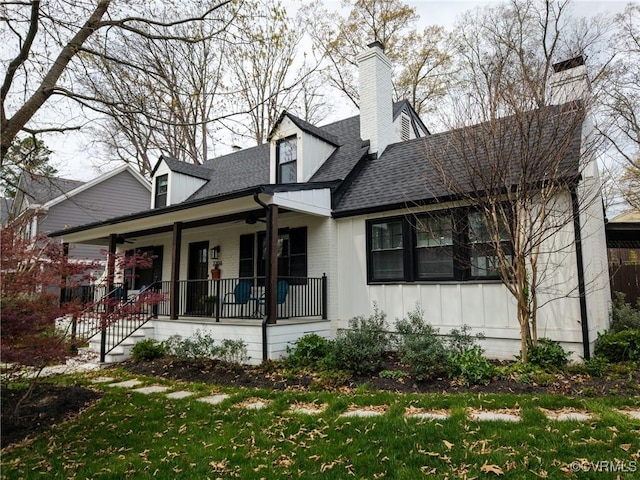 view of front of home with a ceiling fan, a chimney, a shingled roof, board and batten siding, and a porch
