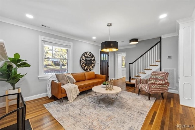 living room with plenty of natural light, visible vents, crown molding, and wood finished floors