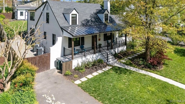 view of front of home featuring a standing seam roof, a porch, a chimney, brick siding, and aphalt driveway