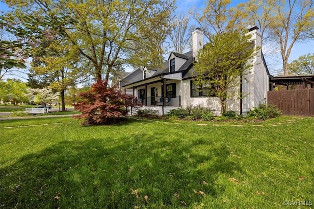 exterior space with covered porch, a lawn, a chimney, and fence