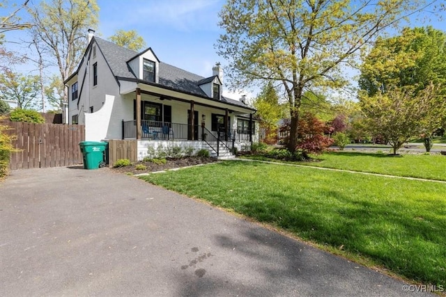 cape cod-style house with a porch, a chimney, fence, a front yard, and aphalt driveway