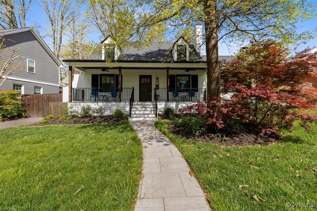 view of front facade featuring ceiling fan, a front yard, covered porch, and fence