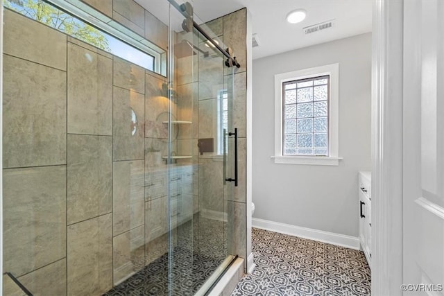 bathroom featuring a shower stall, toilet, vanity, baseboards, and visible vents