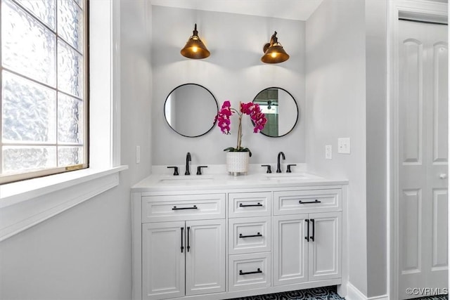bathroom featuring baseboards, a sink, and double vanity