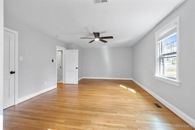 spare room with light wood-type flooring, baseboards, a ceiling fan, and visible vents