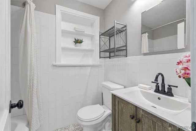 bathroom with wainscoting, toilet, vanity, and tile walls
