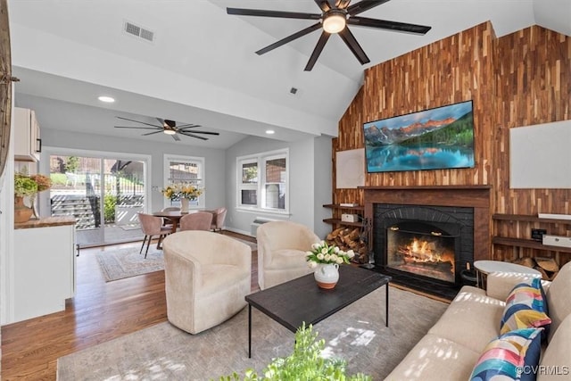 living area featuring ceiling fan, lofted ceiling, visible vents, and light wood finished floors