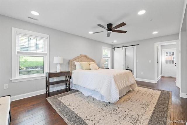 bedroom featuring a barn door, baseboards, dark wood-type flooring, and visible vents