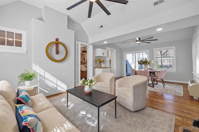 living room with lofted ceiling, visible vents, a ceiling fan, and wood finished floors