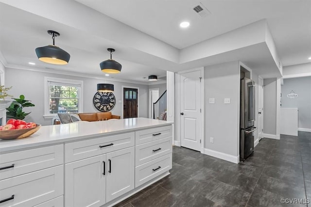 kitchen featuring hanging light fixtures, high quality fridge, light countertops, white cabinets, and visible vents