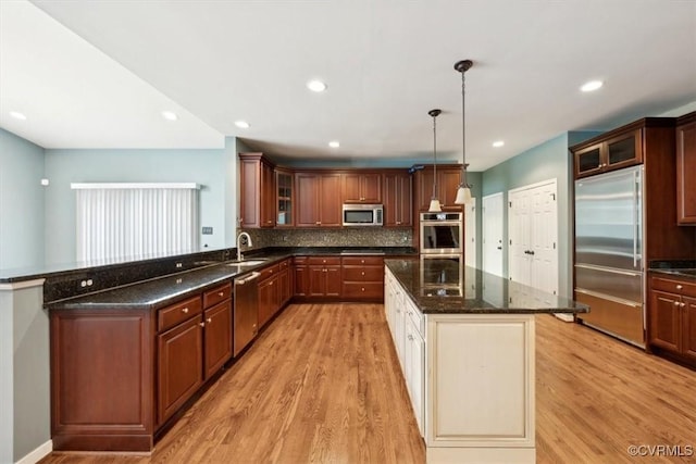 kitchen featuring a sink, glass insert cabinets, light wood-style floors, and stainless steel appliances