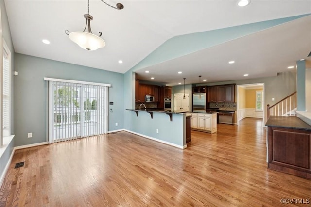 unfurnished living room with visible vents, stairway, a sink, lofted ceiling, and light wood-style floors