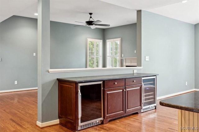 kitchen with dark countertops, ceiling fan, light wood finished floors, and beverage cooler