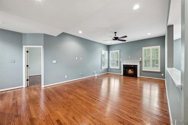 unfurnished living room featuring a ceiling fan, baseboards, recessed lighting, and wood finished floors
