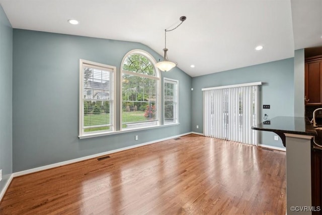 unfurnished dining area with recessed lighting, baseboards, wood finished floors, lofted ceiling, and visible vents