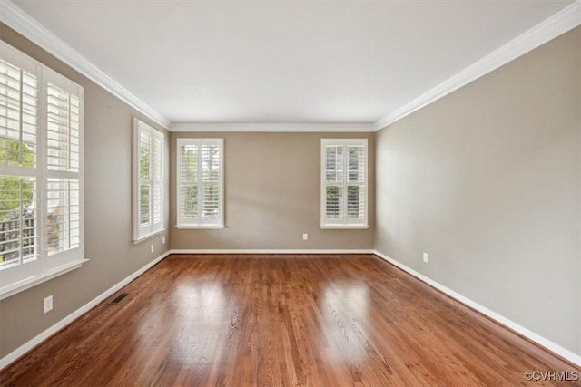 empty room with crown molding, baseboards, visible vents, and wood finished floors