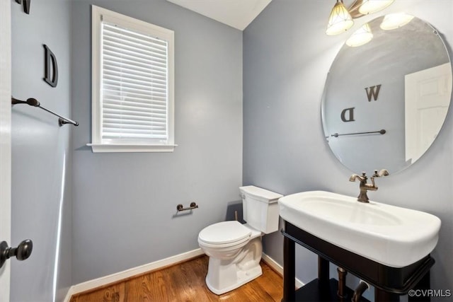 bathroom with baseboards, toilet, and wood finished floors