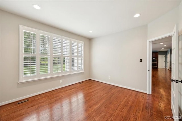 empty room with plenty of natural light, recessed lighting, baseboards, and wood finished floors