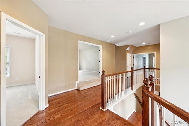 hall with baseboards, recessed lighting, wood finished floors, and an upstairs landing