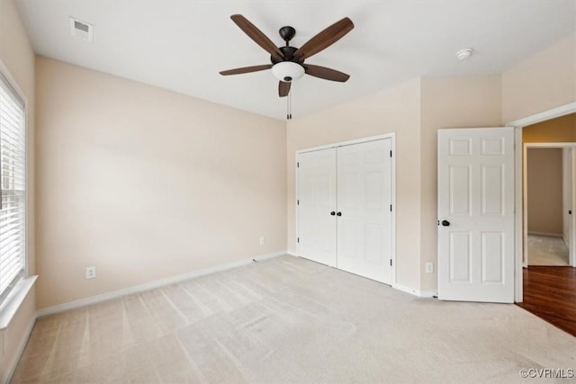unfurnished bedroom featuring carpet floors, baseboards, a closet, and visible vents