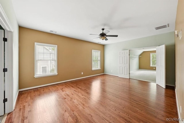 unfurnished bedroom with visible vents, wood finished floors, and multiple windows