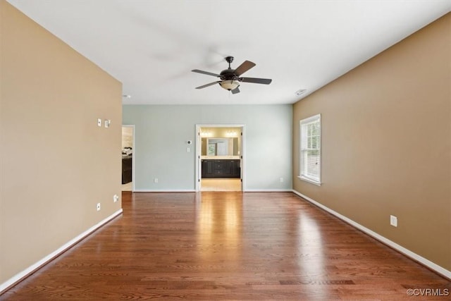 spare room with baseboards, ceiling fan, and wood finished floors