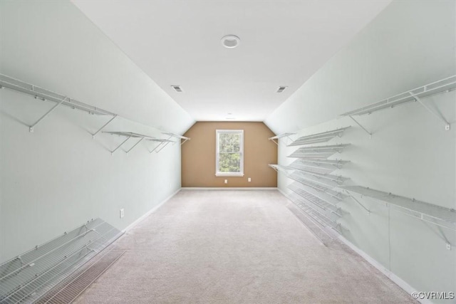 walk in closet with carpet floors, vaulted ceiling, and visible vents