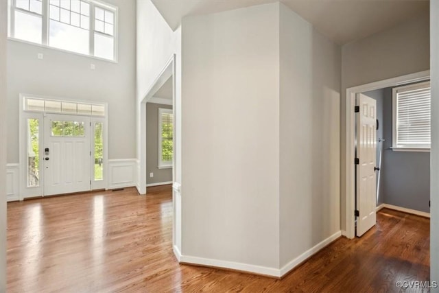 entrance foyer featuring baseboards, a high ceiling, and wood finished floors
