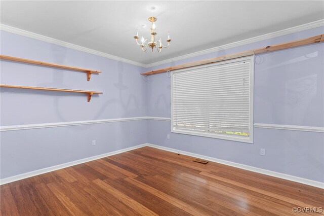 empty room with crown molding, wood finished floors, a notable chandelier, and baseboards