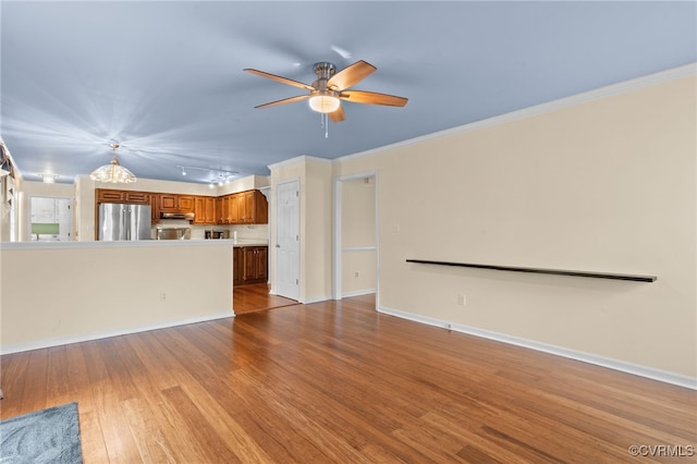 unfurnished living room with baseboards, a ceiling fan, ornamental molding, and wood finished floors