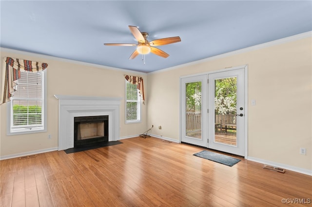 unfurnished living room with visible vents, baseboards, a ceiling fan, crown molding, and hardwood / wood-style floors