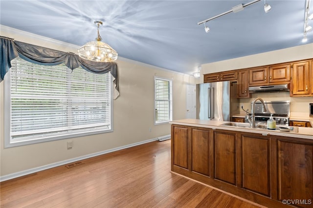kitchen with a chandelier, light countertops, under cabinet range hood, stainless steel appliances, and a sink
