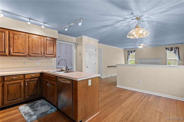 kitchen featuring stainless steel dishwasher, a peninsula, a sink, and a healthy amount of sunlight