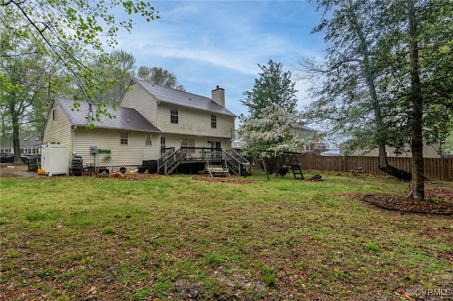rear view of property with a deck, a lawn, a chimney, fence, and stairs